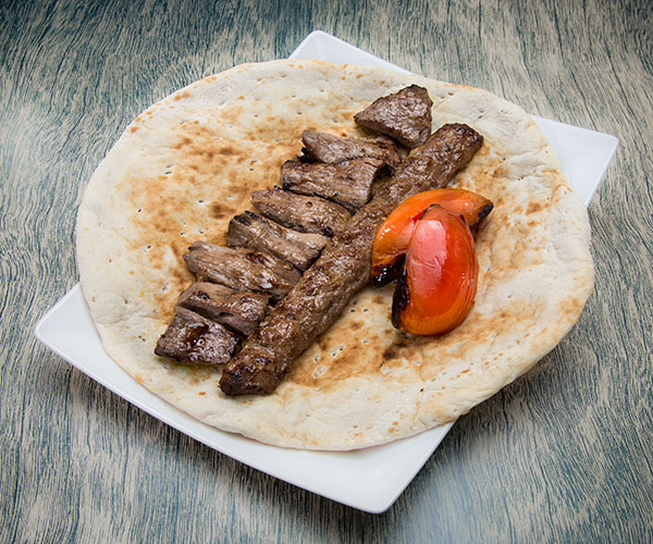 Combo meal of meat and two tomato slices on pita bread